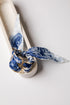 White ceramic with a blue and white patterned cloth tied around it on a light gray background
