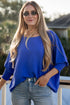 Woman wearing a blue sweater and sunglasses on a balcony