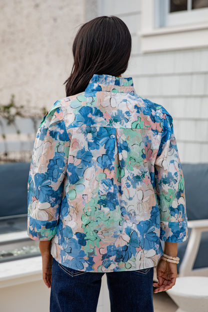 Person wearing a colorful floral jacket standing outdoors.