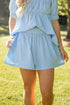 Person wearing a light blue outfit with shorts in an outdoor setting