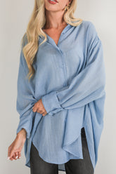Woman wearing a light blue button-up shirt against a plain background