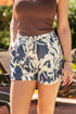 Person wearing blue and white patterned shorts with a blurred outdoor background
