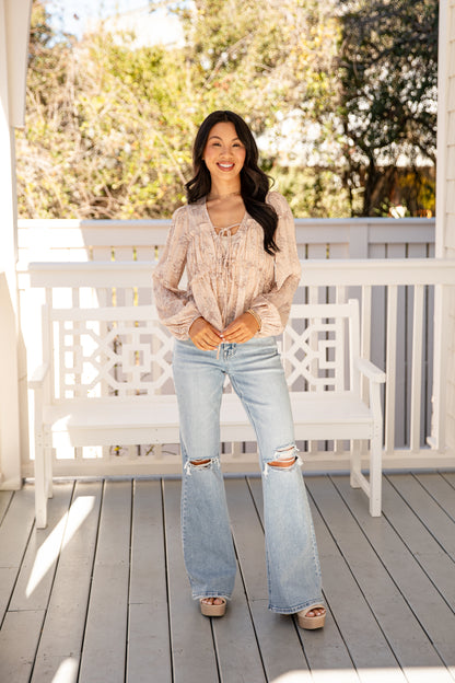 Woman standing on a wooden deck with a white bench and greenery in the background
