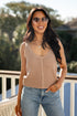 Woman wearing a beige crochet top and blue jeans on a balcony