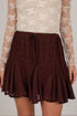 A close-up of a model wearing a dark brown lace and chiffon flared skirt with a drawstring waist, paired with a cream lace long-sleeve top.
