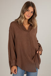 Woman wearing a brown button-up shirt against a plain background