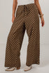 A person wearing brown wide-leg pants with a white polka dot pattern, styled with a white top and beige heeled shoes against a plain white studio background.