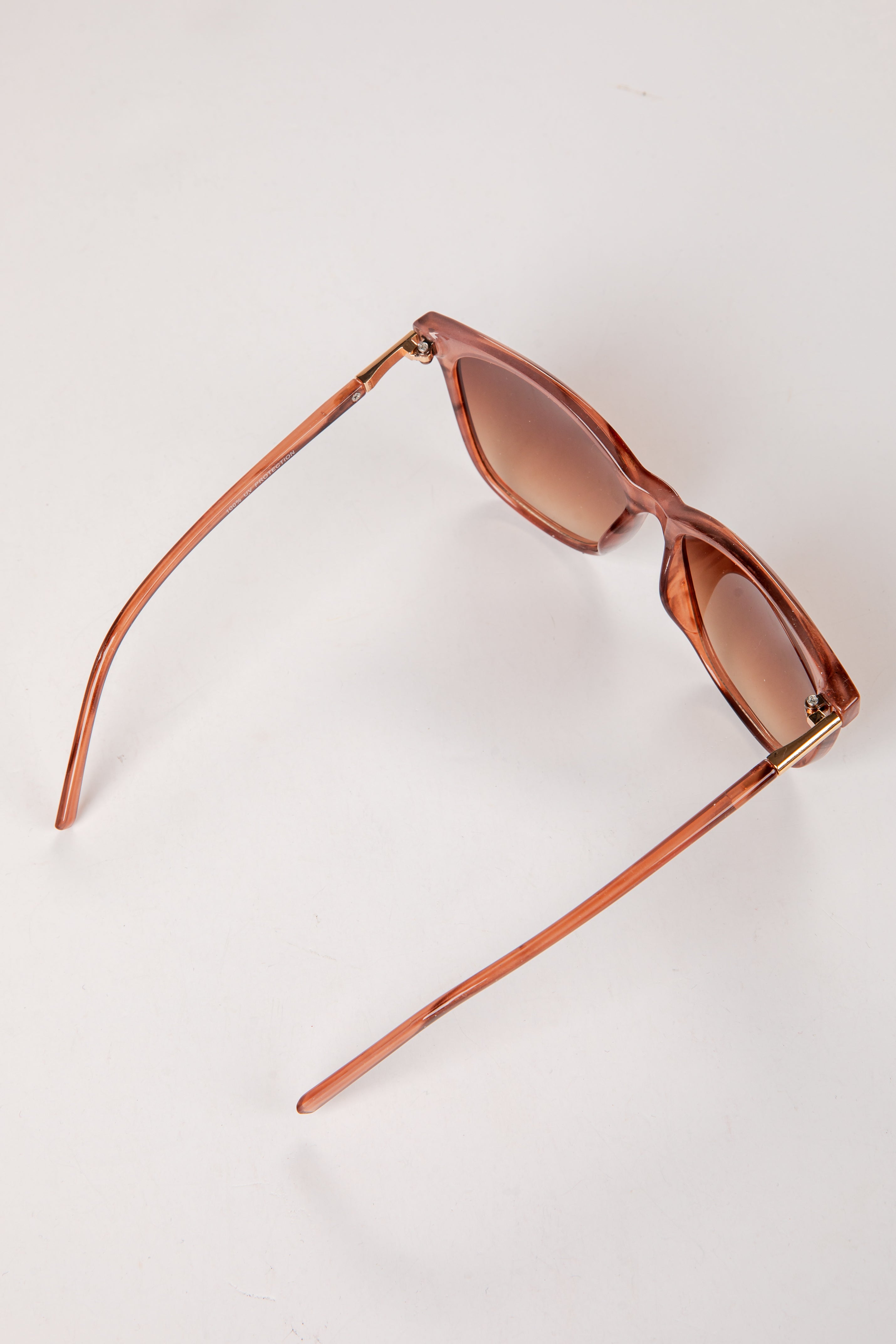 Sunglasses with brown frame and lenses on a light beige background