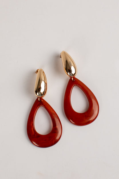 A pair of teardrop-shaped drop earrings with glossy translucent red resin bodies and polished gold-tone metal posts, shown on a plain light background.