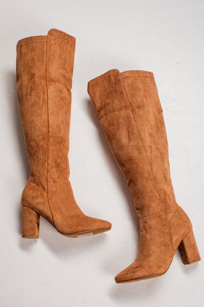 A pair of knee-high suede boots in a warm camel brown color, featuring a block heel and pointed toe, displayed on a light off-white background.