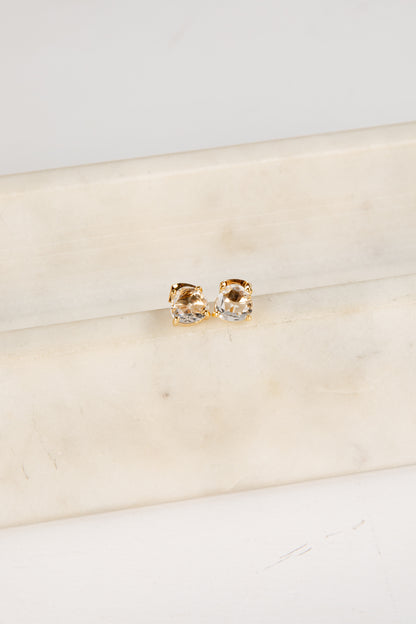 Gold and silver earrings on a beige fabric background