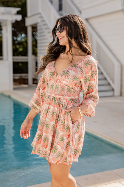Woman in a pink floral dress standing by a pool