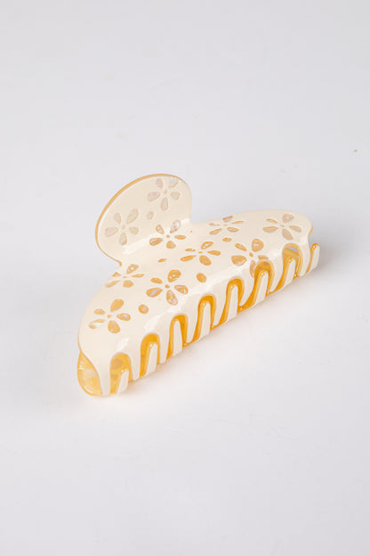 yellow claw clip with floral patterns on a light gray background