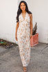Woman wearing a floral dress standing against a white wall.
