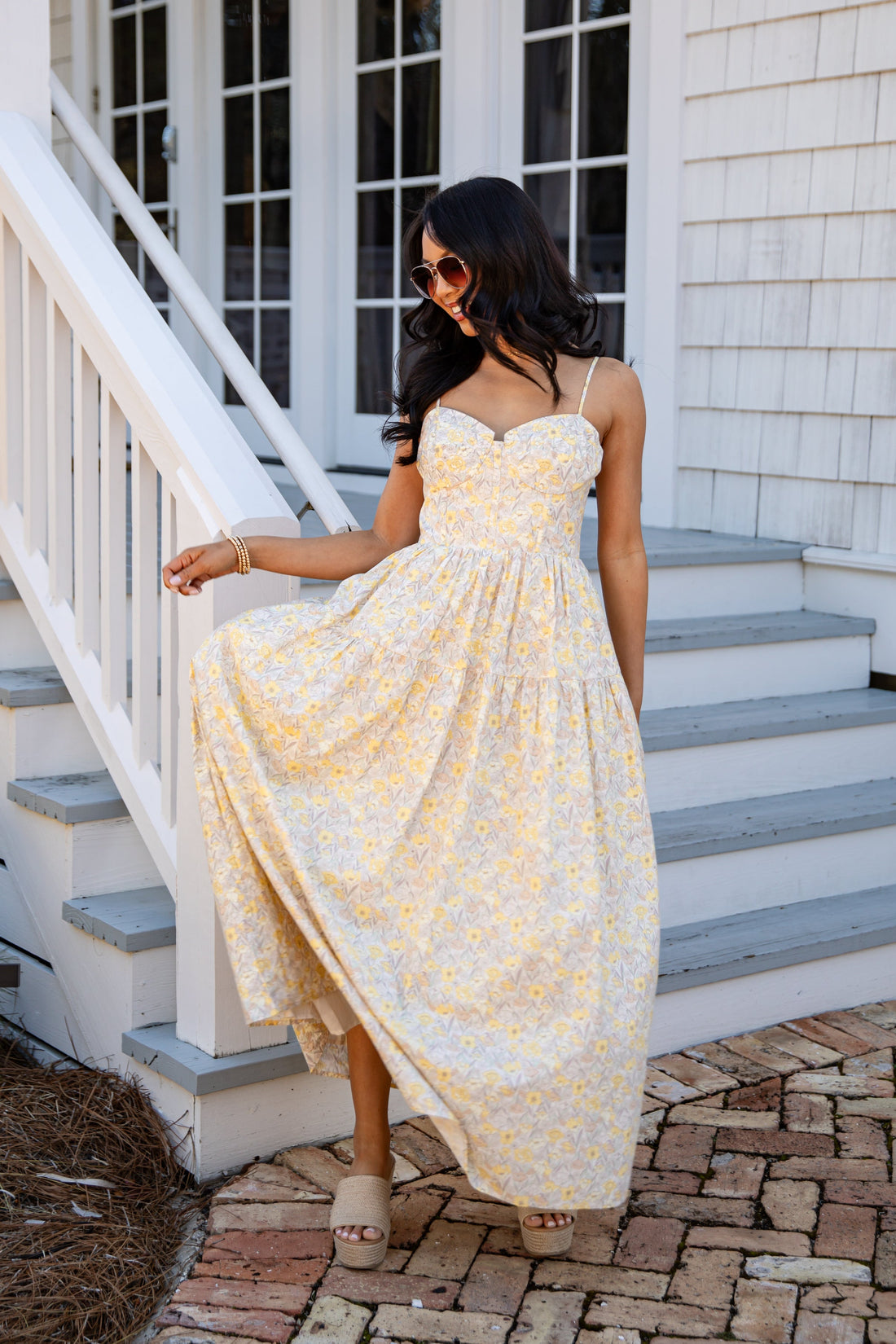 Woman in a yellow dress standing on a staircase outside a house