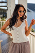 Woman wearing a white sleeveless top and plaid pants on a balcony.