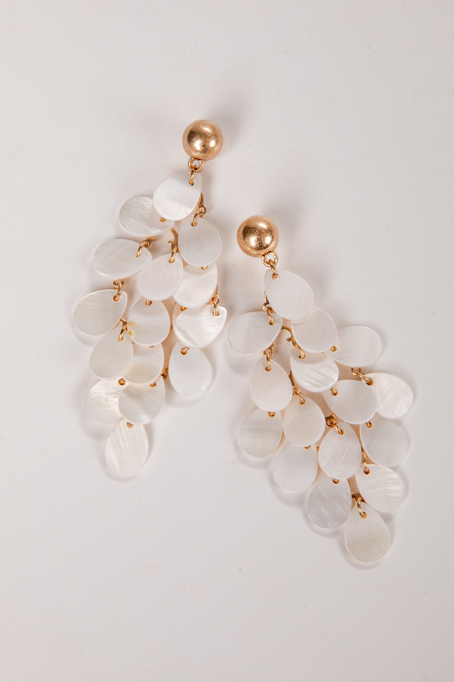 Elegant earrings with white stones and gold accents on a light gray background