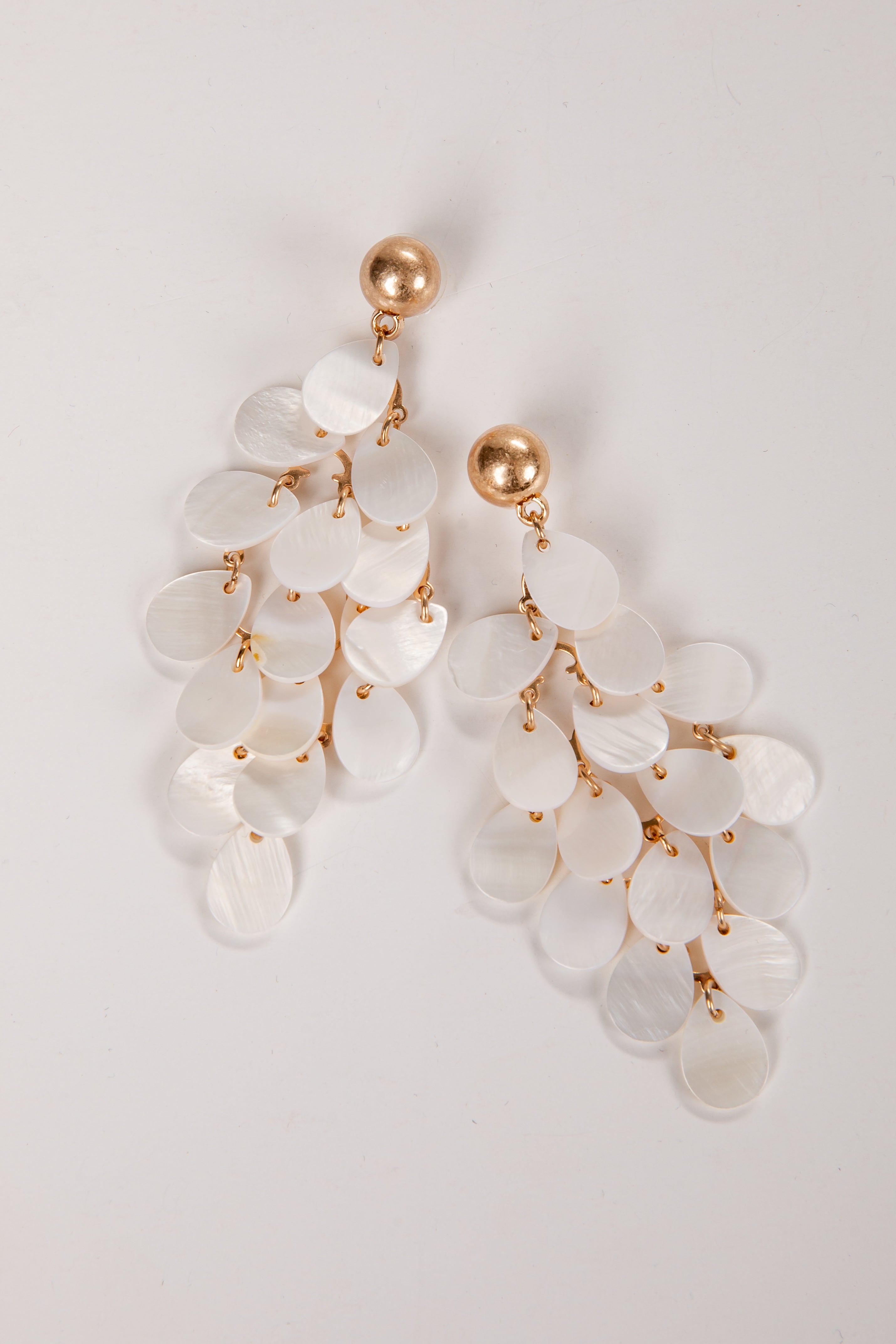 Elegant earrings with white stones and gold accents on a light gray background