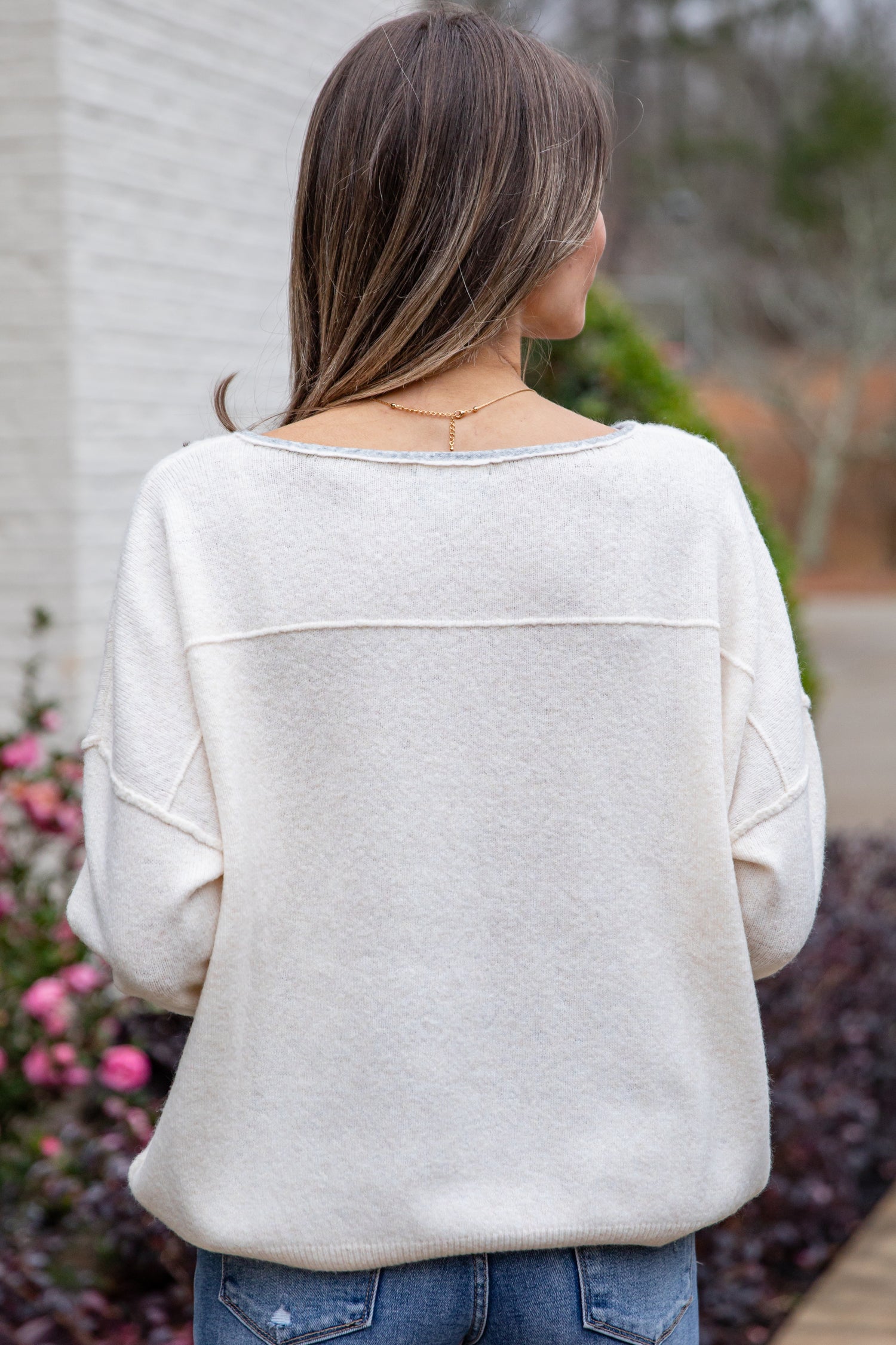 Person wearing a light gray sweater with a blurred outdoor background
