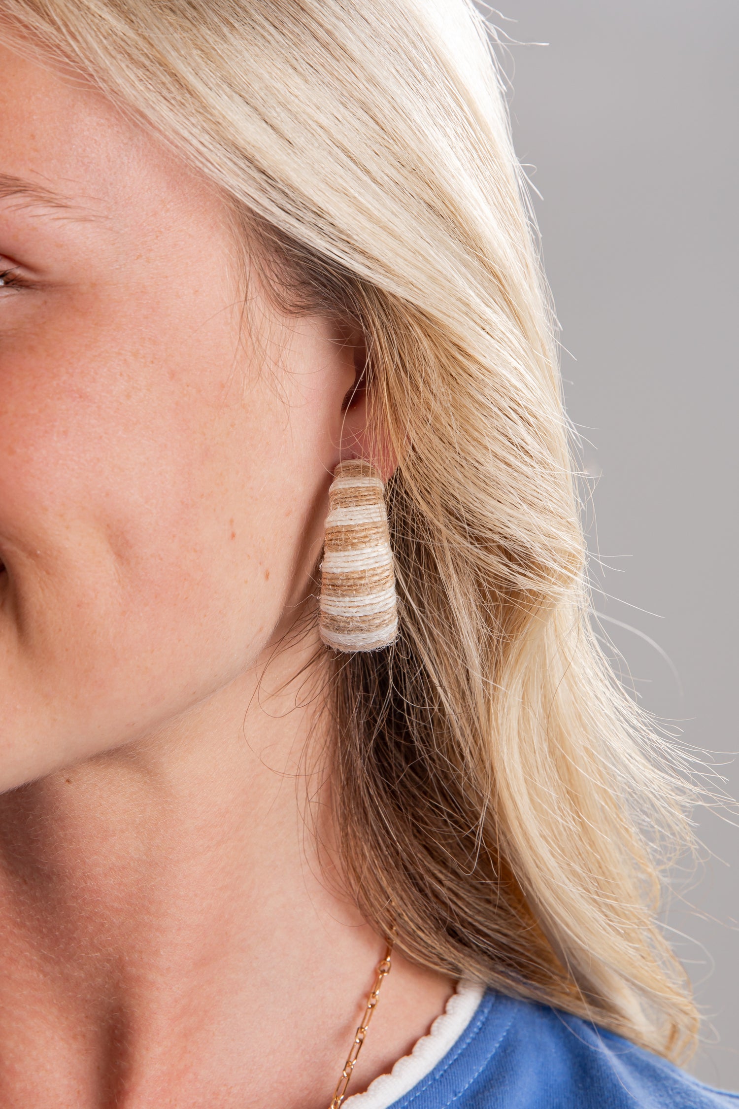Close-up of a woman wearing striped earrings with a neutral background