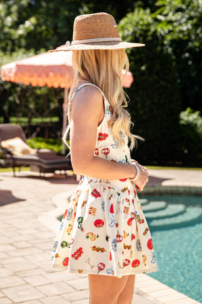 Woman in a floral dress and straw hat by a poolside