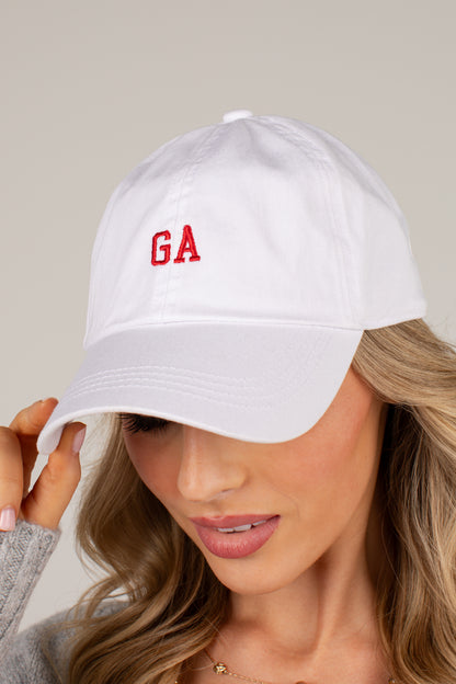 A woman wearing a white baseball cap with red embroidered letters &