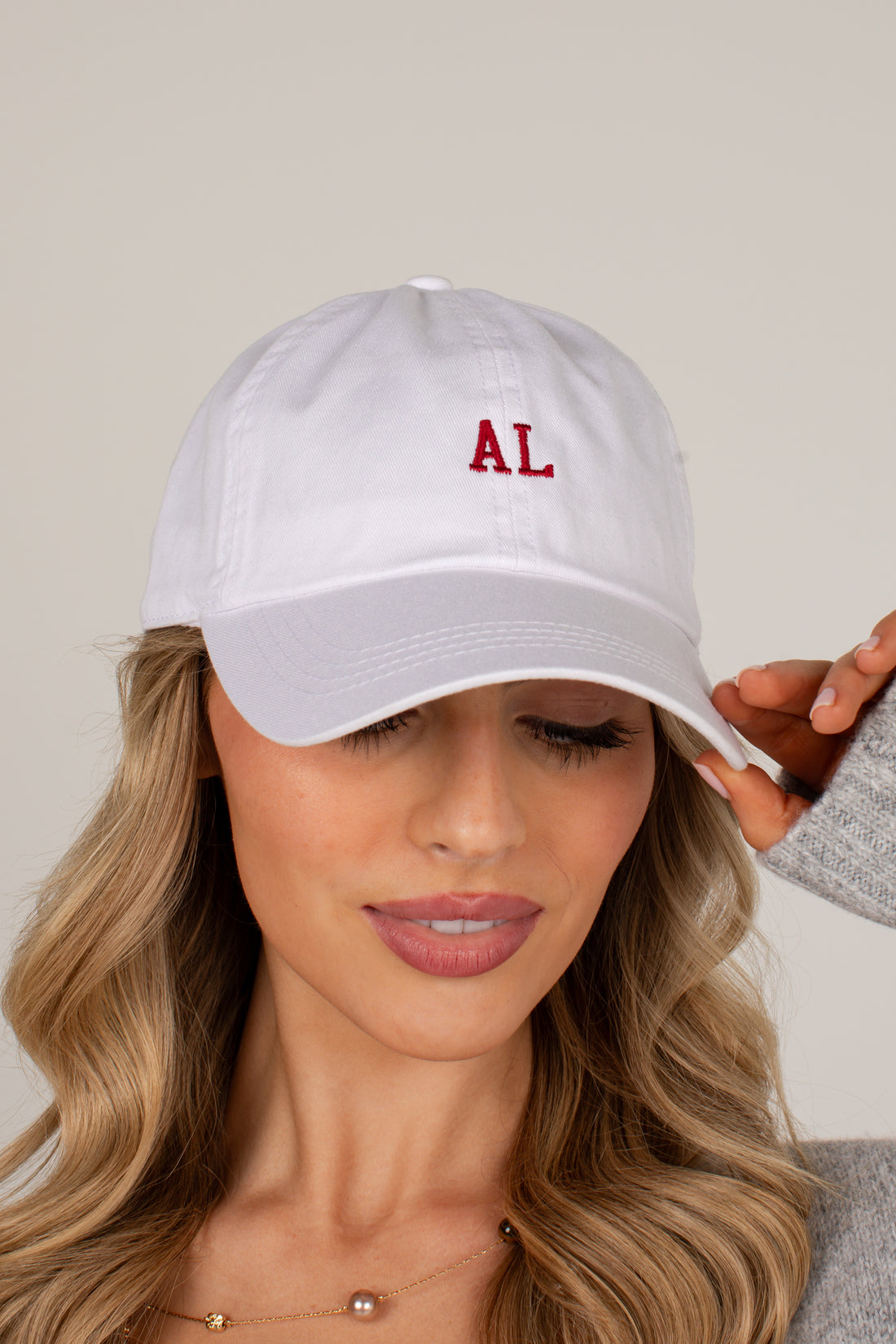 A woman wearing a white baseball cap with red embroidered letters &