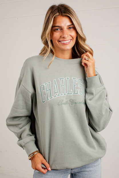 A woman wearing a sage green sweatshirt with &