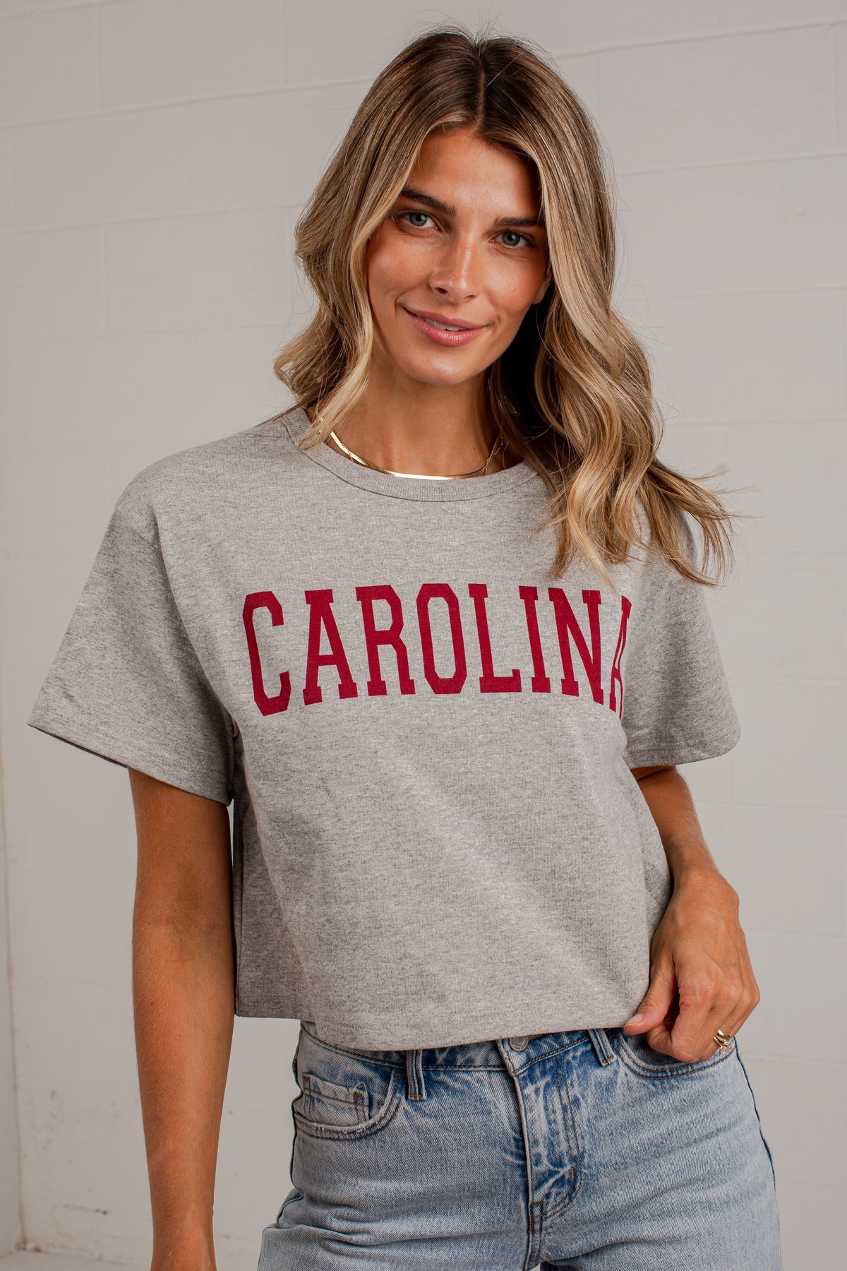 A woman wearing a heather gray cropped t-shirt with &