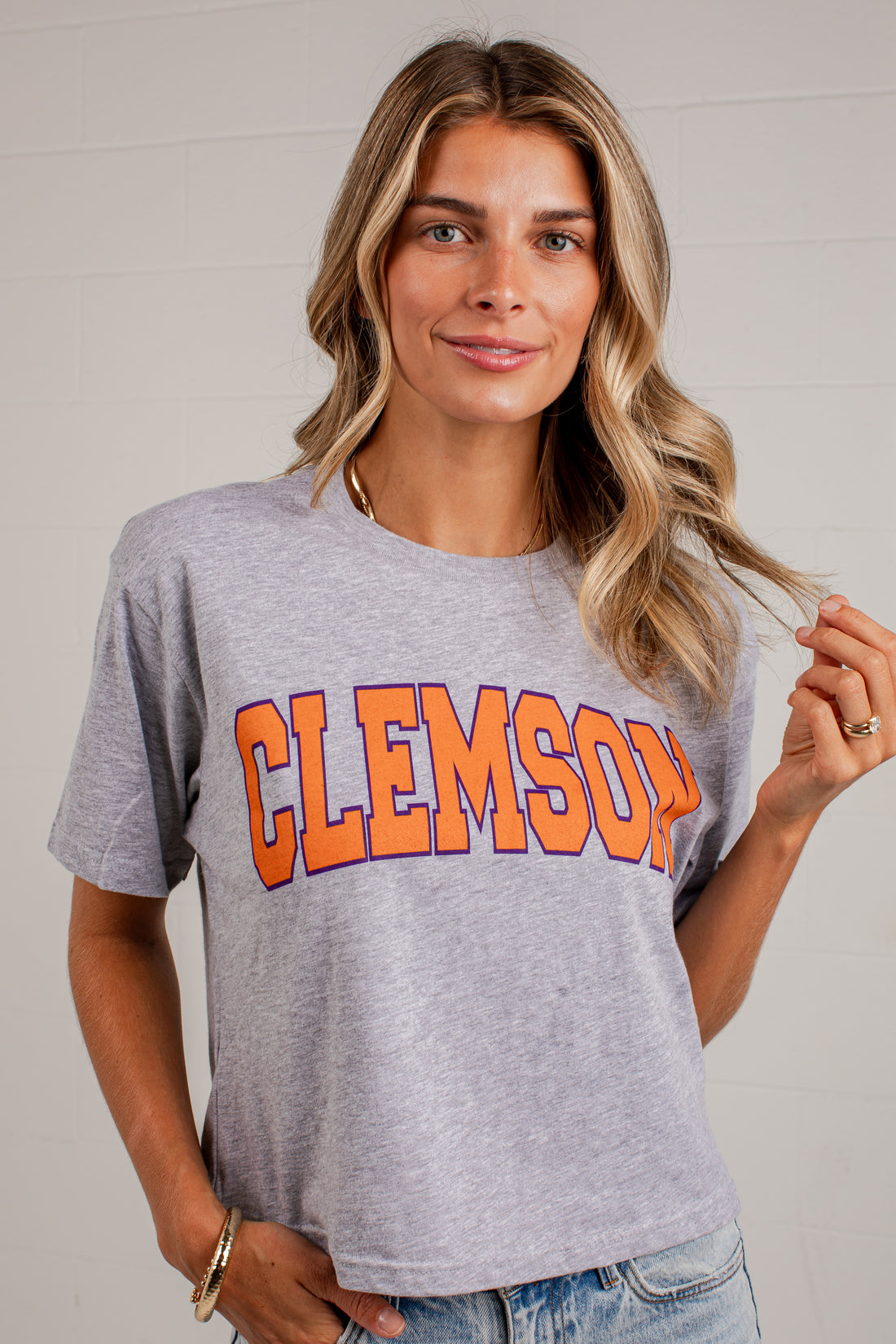 A woman wearing a heather gray Clemson Tigers graphic t-shirt with &