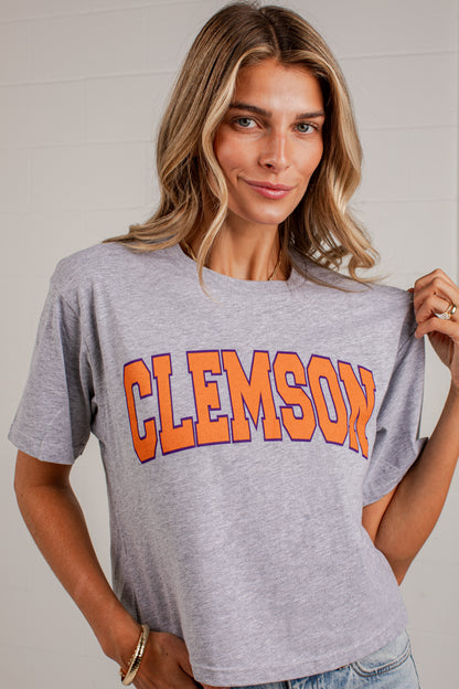 A woman wearing a heather gray Clemson athletic t-shirt with &