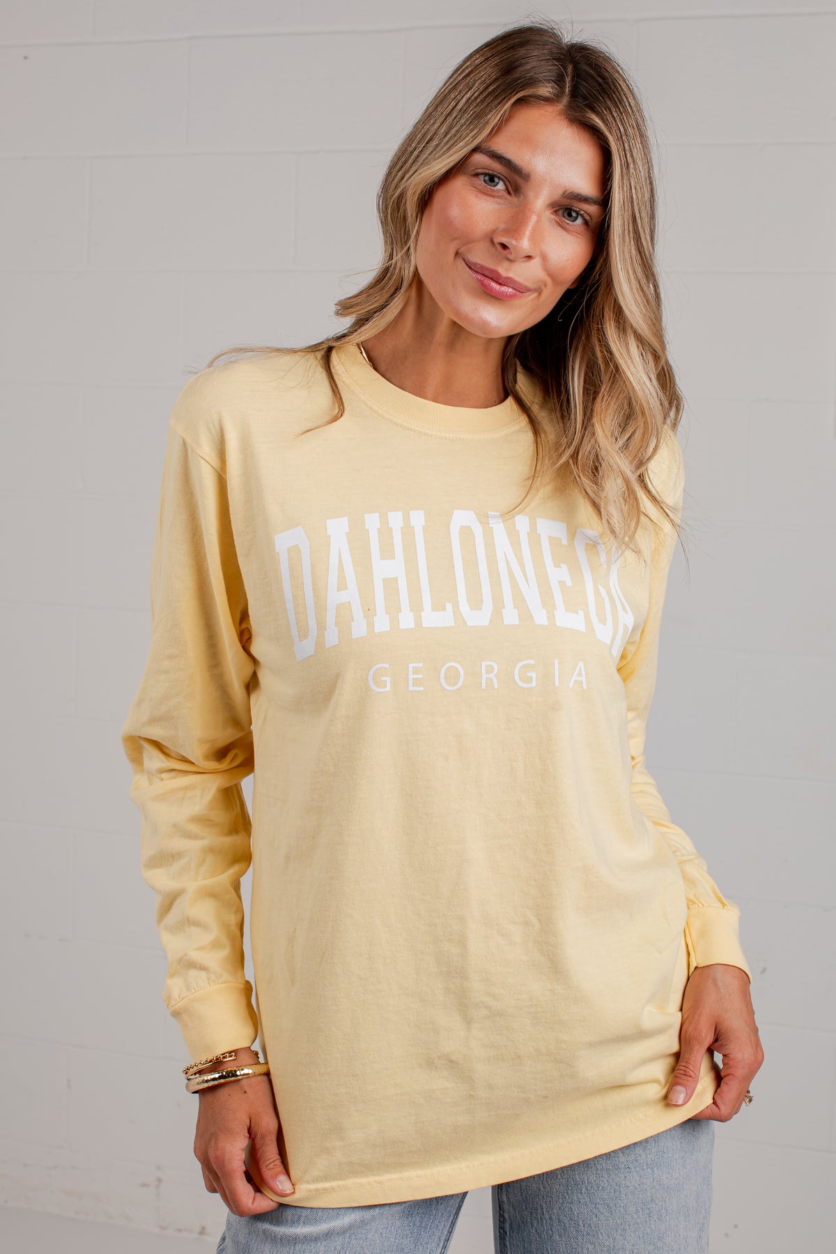 A woman wearing a pale yellow long-sleeve t-shirt with &