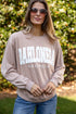 Woman wearing a beige sweatshirt with &