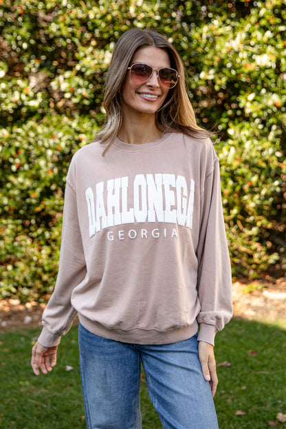 Woman wearing a beige sweatshirt with &