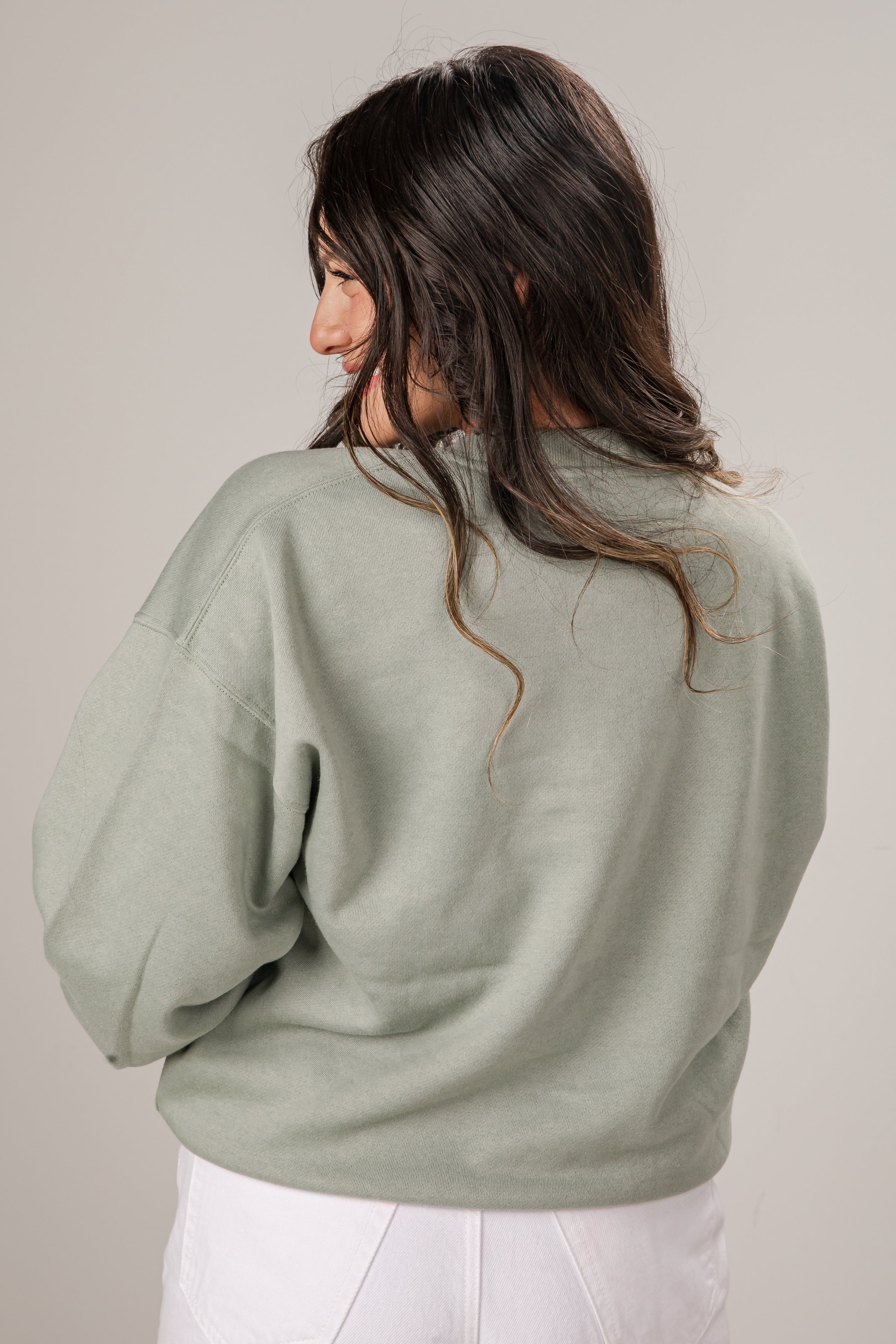 Woman wearing a light green sweater against a plain background