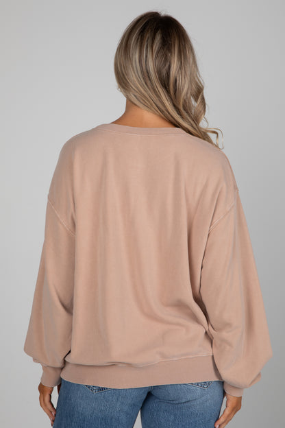 Person wearing a beige sweater and blue jeans on a plain background