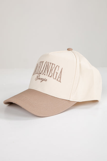 Two-tone beige and brown cap with text on a light gray background