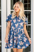 Woman wearing a blue floral dress standing in front of glass doors.