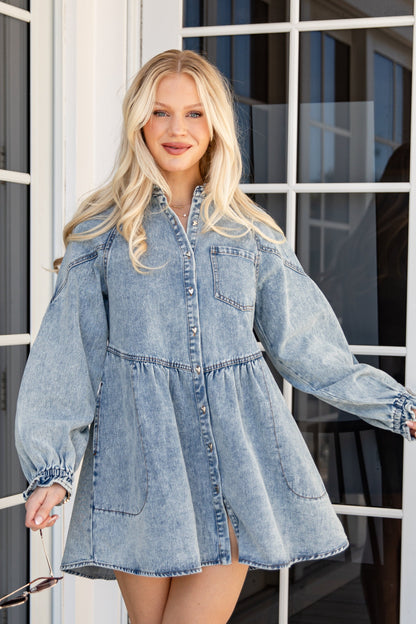 Woman wearing a denim dress standing on a wooden deck.