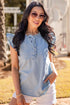 Woman wearing a light blue denim top and white shorts outdoors.