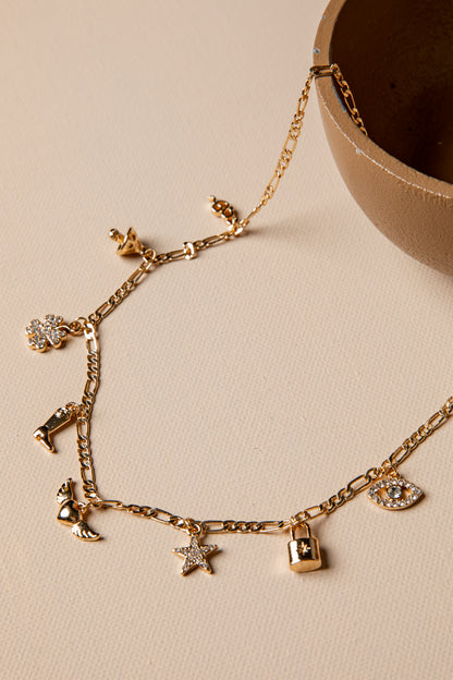 Gold bracelet with various charms on a beige surface