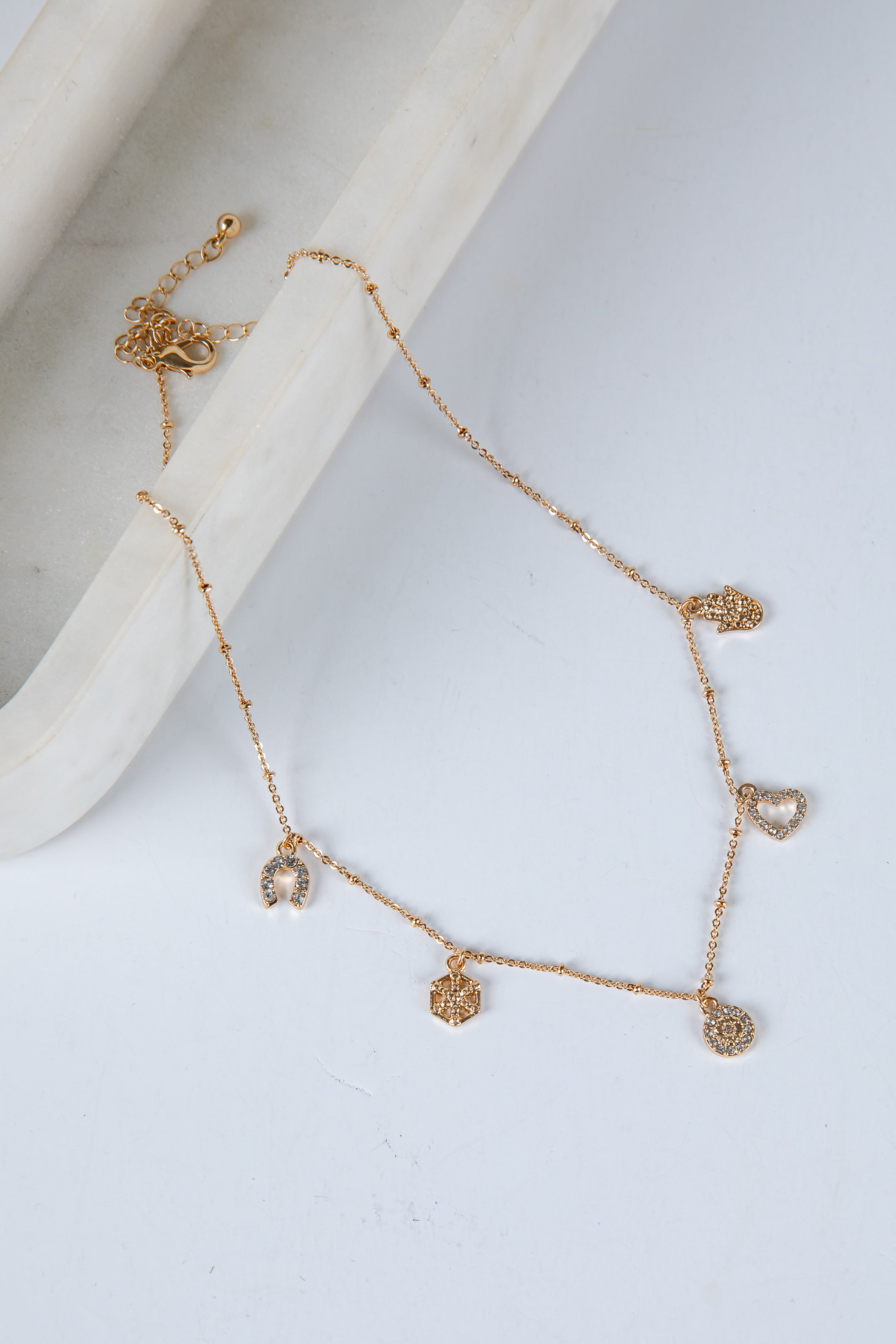Gold necklace with heart-shaped pendants on a light gray background