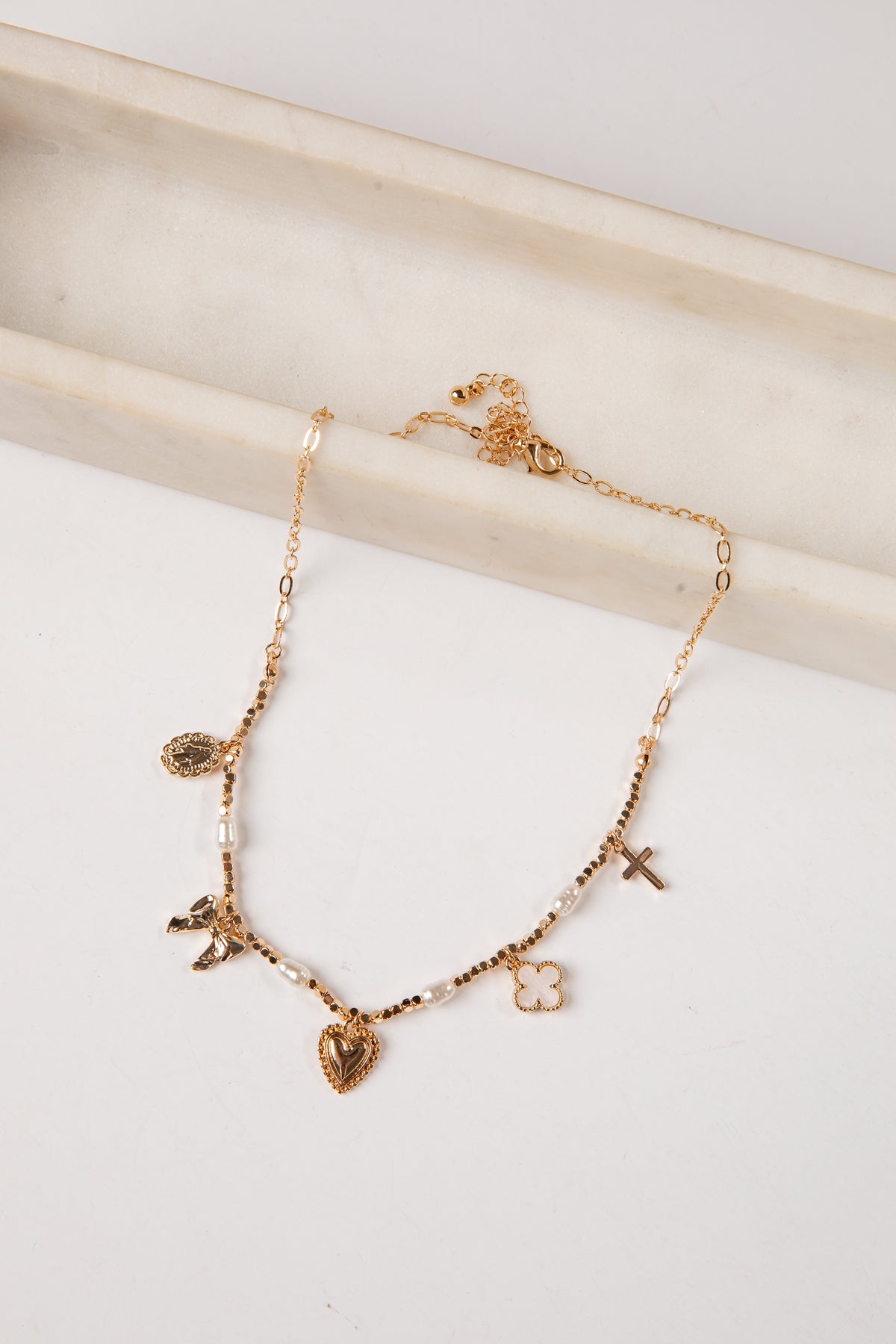 Gold necklace with various charms on a white surface