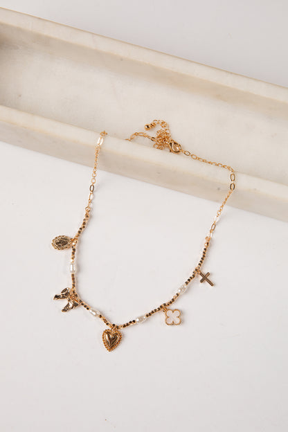 Gold necklace with various charms on a white surface