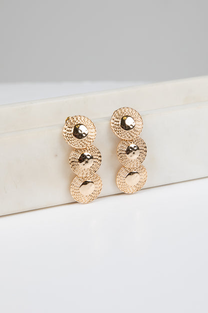 Rose gold earrings on a white surface with a gray background