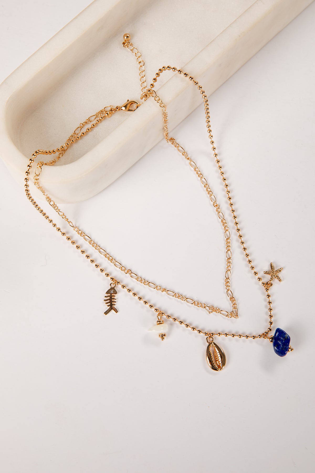 Gold necklace with charms on a white surface