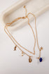 Gold necklace with various charms on a white surface