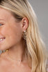 Close-up of a woman wearing gold earrings with a gray background