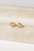 Heart-shaped gold earrings on a beige marble surface