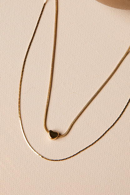 Gold necklace with a heart pendant on a beige background